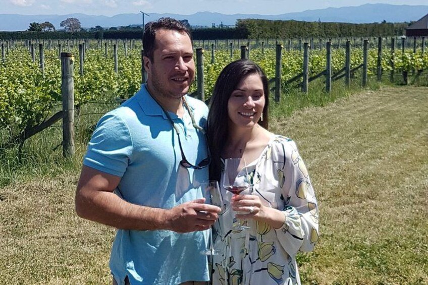 Two people standing in a vineyard with rows of grapevines. 2