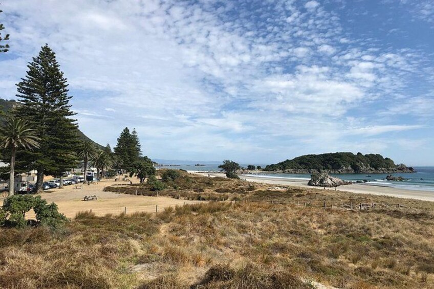 Un paysage côtier avec une plage, une petite île et un ciel dégagé. 5