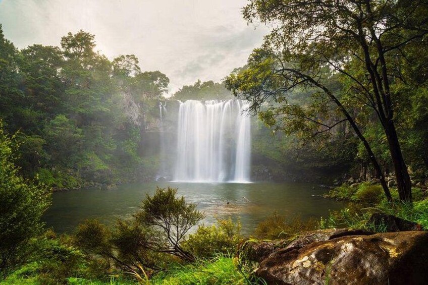 A waterfall surrounded by lush greenery and a calm body of water. 2