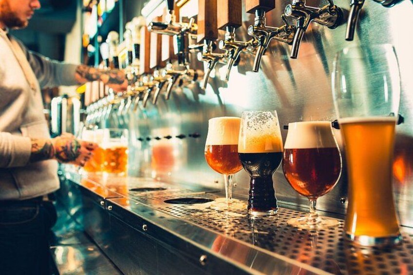 A bar with multiple taps dispensing beer into glasses. 5