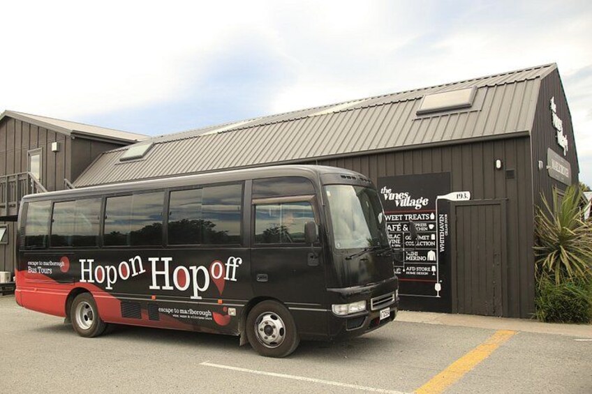 A black van with 'Hopon Hopoff' branding parked in front of a building with a signboard. 4