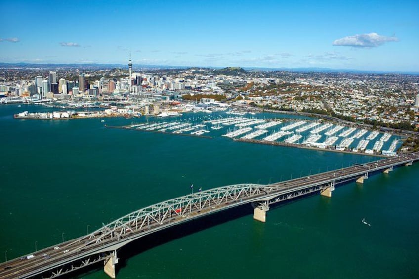 Un puente que cruza una masa de agua, con un puerto deportivo y un paisaje urbano al fondo. 2