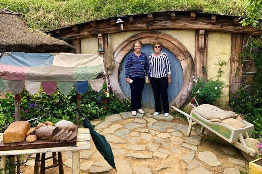 A hobbit-style house with a round door, a table with baked goods, and a wheelbarrow. 3