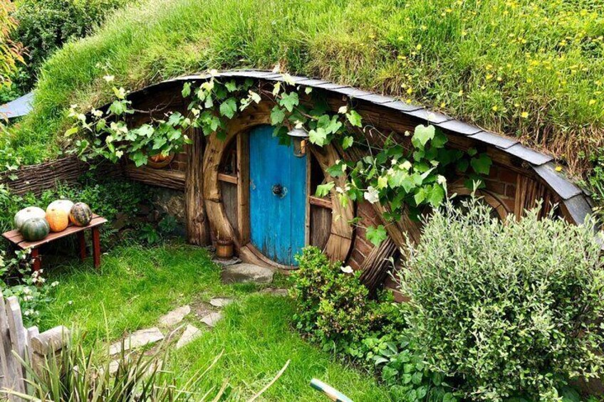 A Hobbit-style house with a blue door, surrounded by greenery and a stone path. 5
