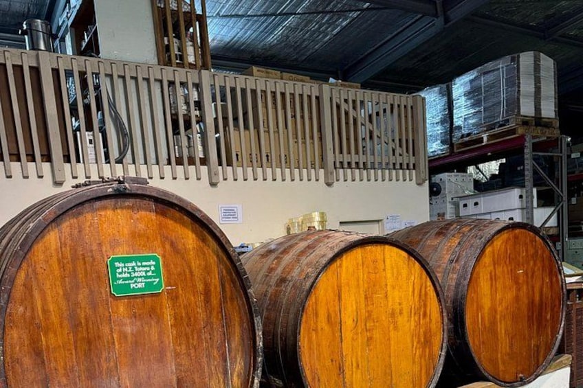 Wooden barrels in a storage area with a metal rack and a sign. 3