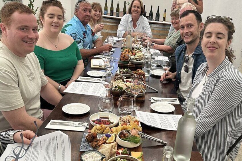 A group of people seated around a table with food and wine. 5