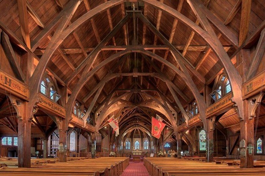 A church interior with wooden pews, arched ceiling, stained glass windows, and banners. 2