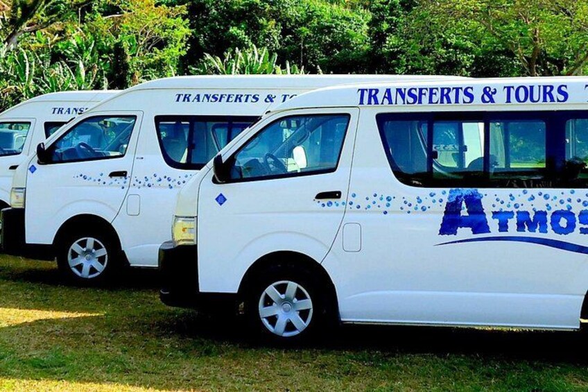 Three white vans with 'TRANSFERTS & TOURS' and 'ATMOS' branding parked on grass. 2