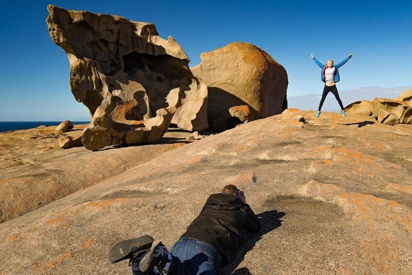 A person lying on the ground with a large rock formation in the background. 3