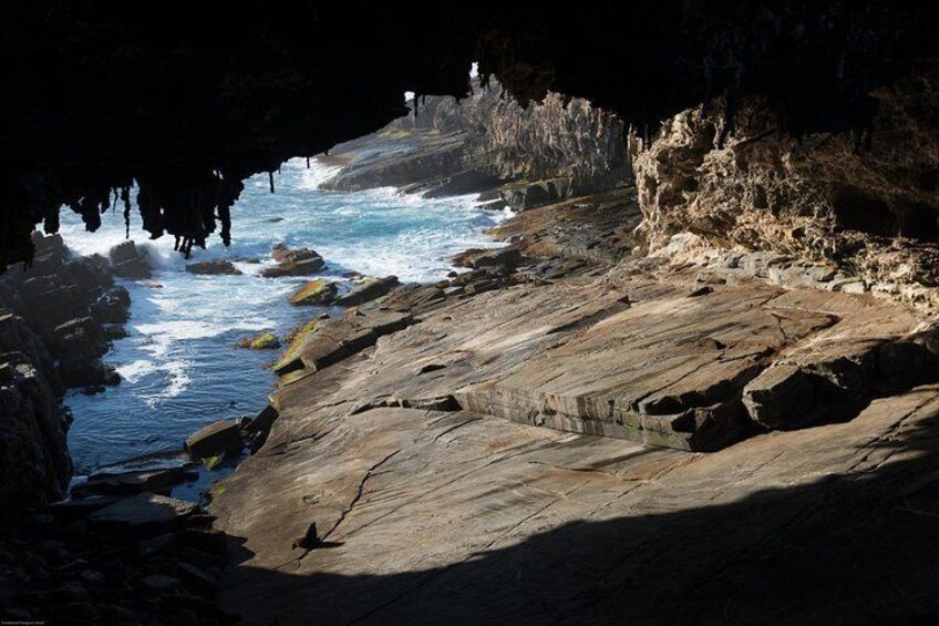 A rocky coastline with waves crashing against the shore and a cave entrance. 3