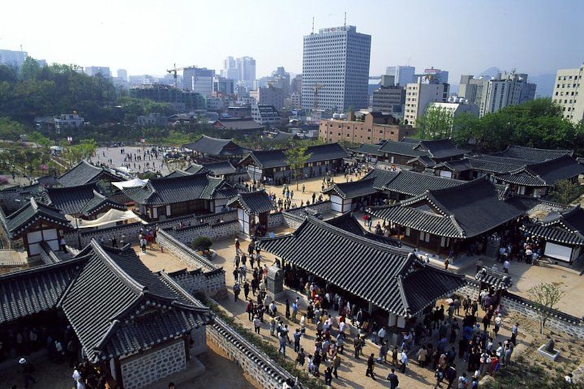 En traditionell koreansk by med trähus och en modern stadsbild i bakgrunden. 5