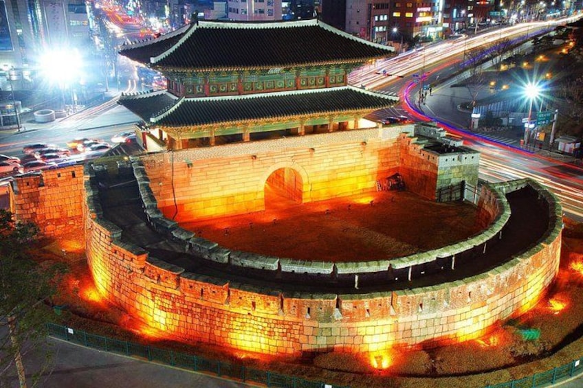 Ett traditionellt koreanskt palats med en rund innergård, omgivet av en stenmur och upplyst av gatlyktor. 3