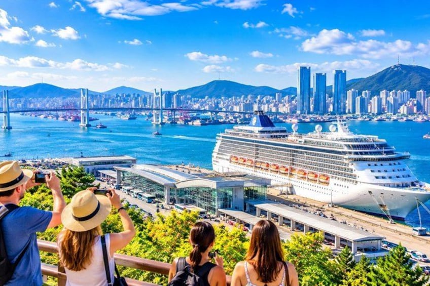 A cruise ship docked at a port with a cityscape in the background. 1