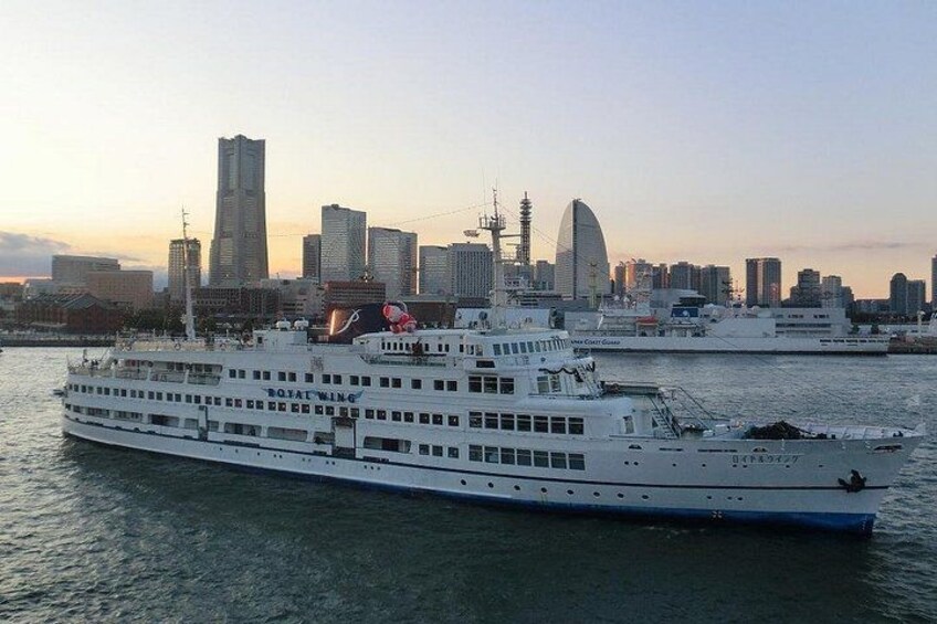 A large white cruise ship with multiple decks and a city skyline in the background. 4