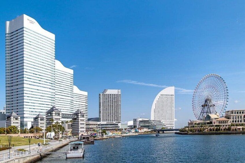 A waterfront cityscape with modern buildings, a large Ferris wheel, and a calm river. 3