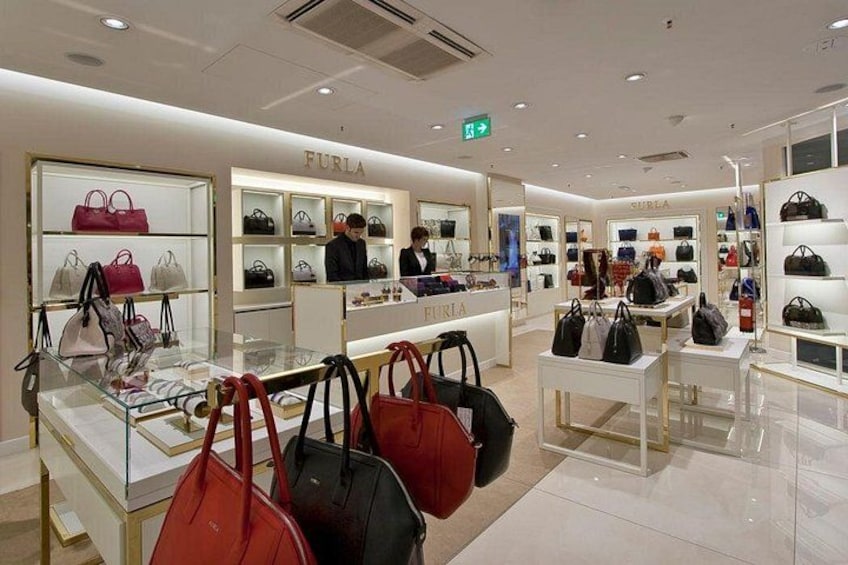A luxury handbag store with display cases and shelves of handbags. 2