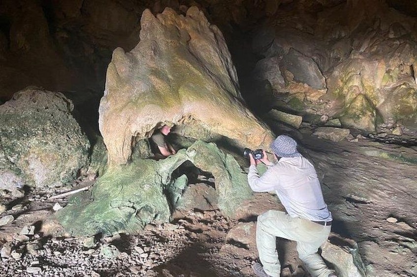 A person taking a photograph inside a cave with large rock formations. 3