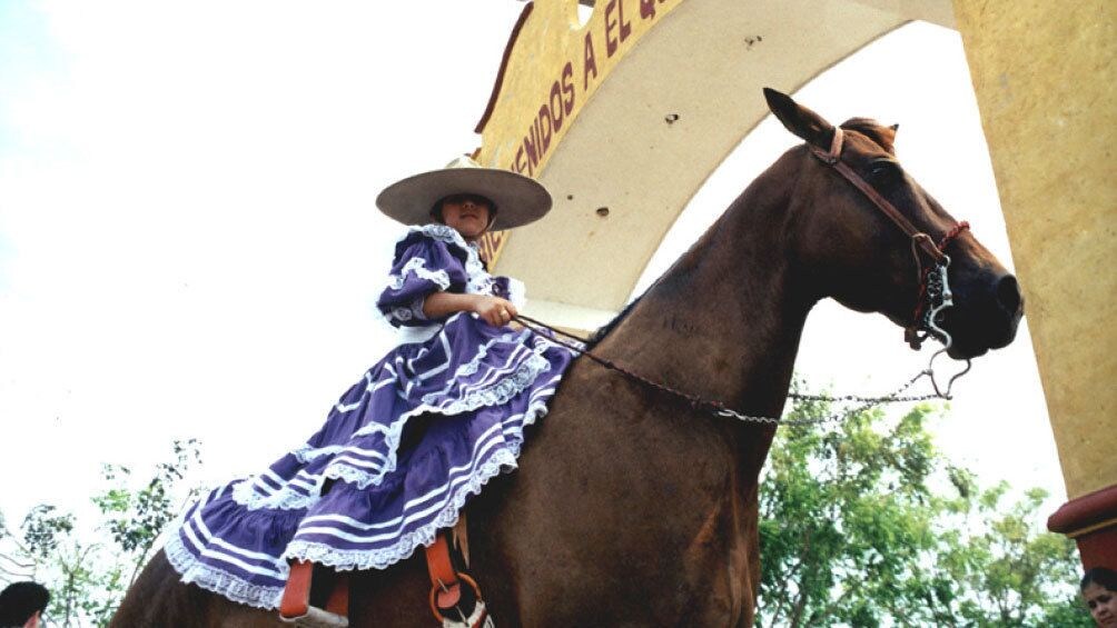 Girl in a traditional dress riding a horse at El Quelite  