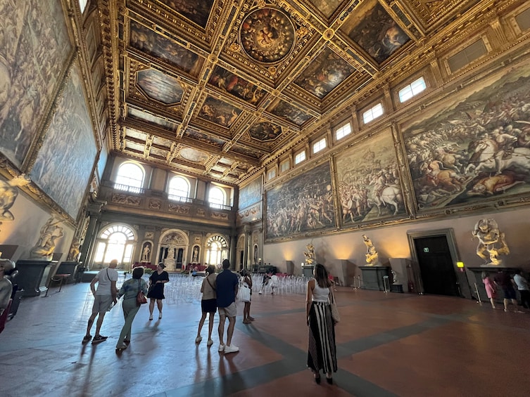 A grand hall with ornate ceilings, large frescoes, and classical statues. 5