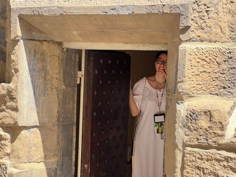 A person standing in a doorway with a textured stone wall. 1