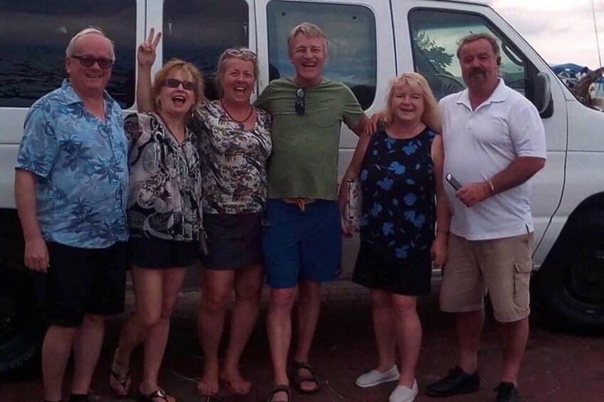 Un grupo de personas de pie frente a un vehículo blanco. 5