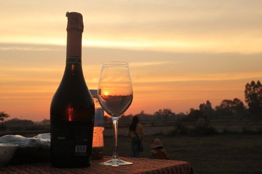A bottle of wine and a glass on a table with a sunset in the background. 5