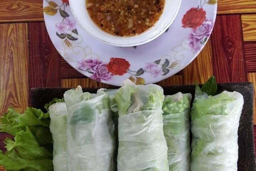A plate of fresh spring rolls with a bowl of dipping sauce. 1