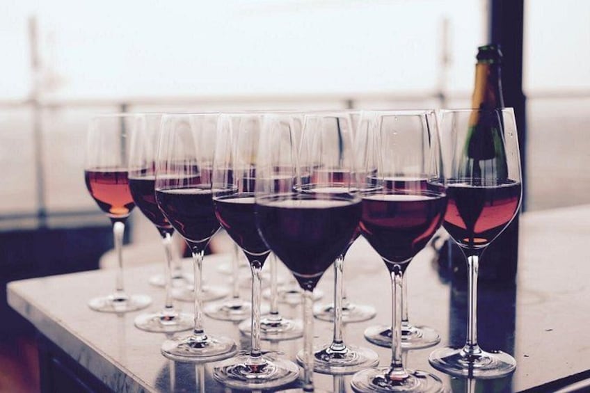 Una fila de copas de vino tinto sobre una mesa. 1