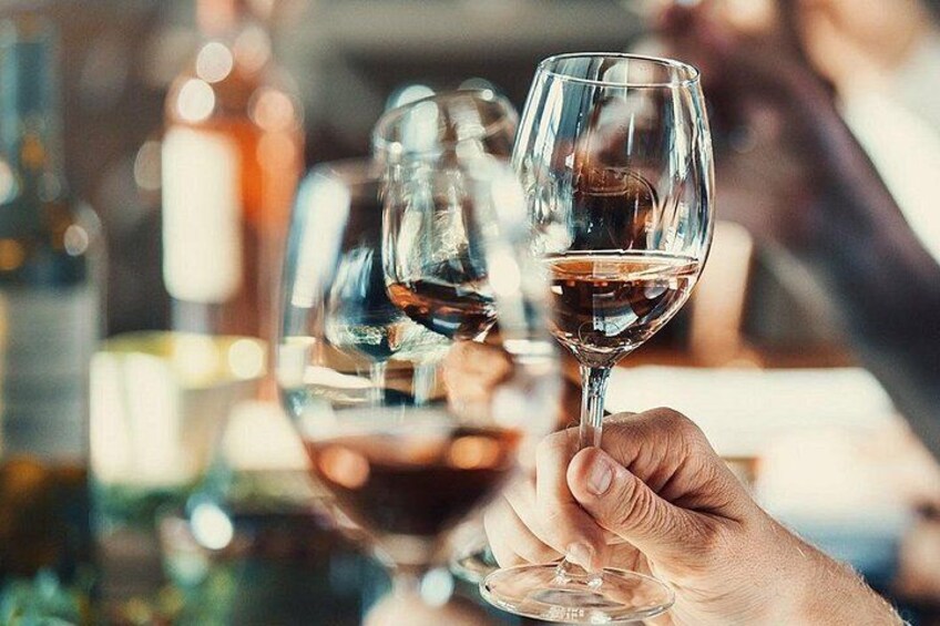 Una persona sosteniendo una copa de vino con líquido, probablemente vino, en un bar con botellas al fondo. 3