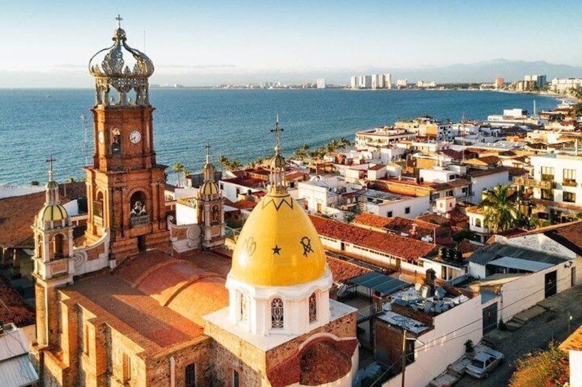 A coastal town with a prominent church featuring a yellow dome and a clock tower. 1