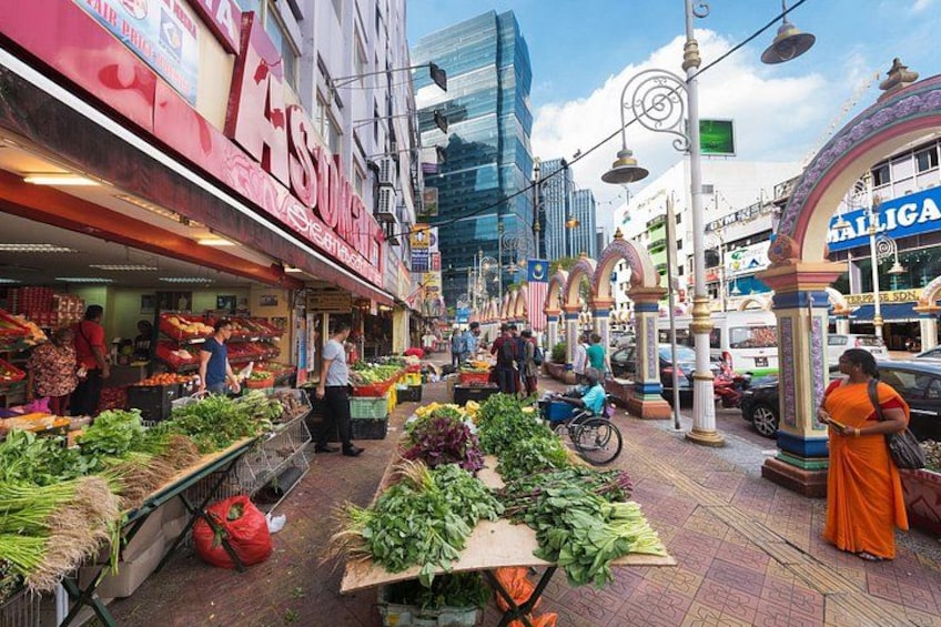 A bustling street market with vendors selling fresh produce, a prominent red storefront, and a blue sign. 2