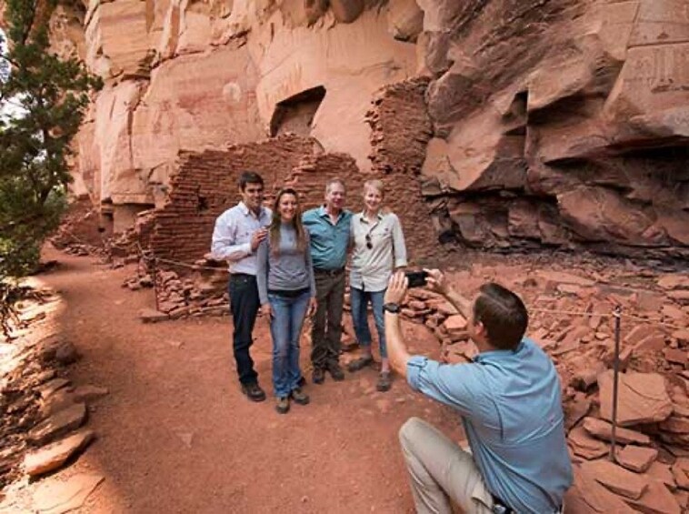 A group of people standing in front of a rock formation with a photographer taking their photo. 3