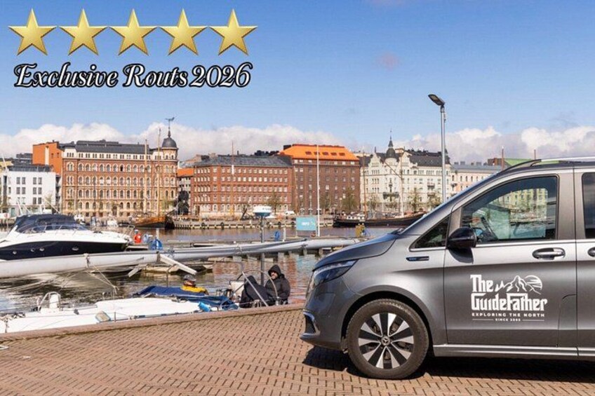 Een auto met het logo 'The Guidefather' geparkeerd aan een waterkant, met boten en gebouwen op de achtergrond. 1