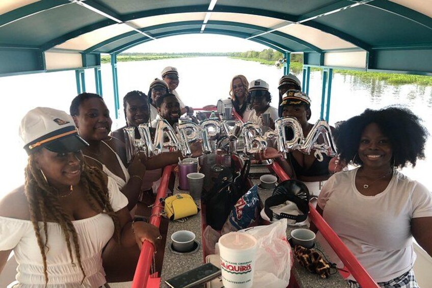 A group of people on a boat with 'HAPPY BIRTHDAY' balloons. 3