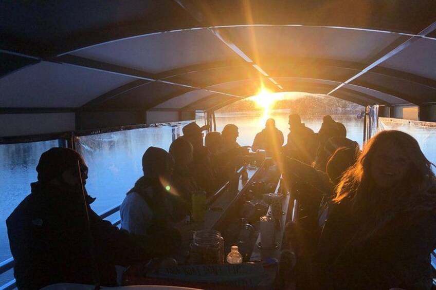 A group of people on a boat with a sunset in the background. 2