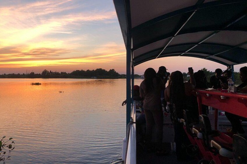 A sunset over a calm lake with people on a boat. 4