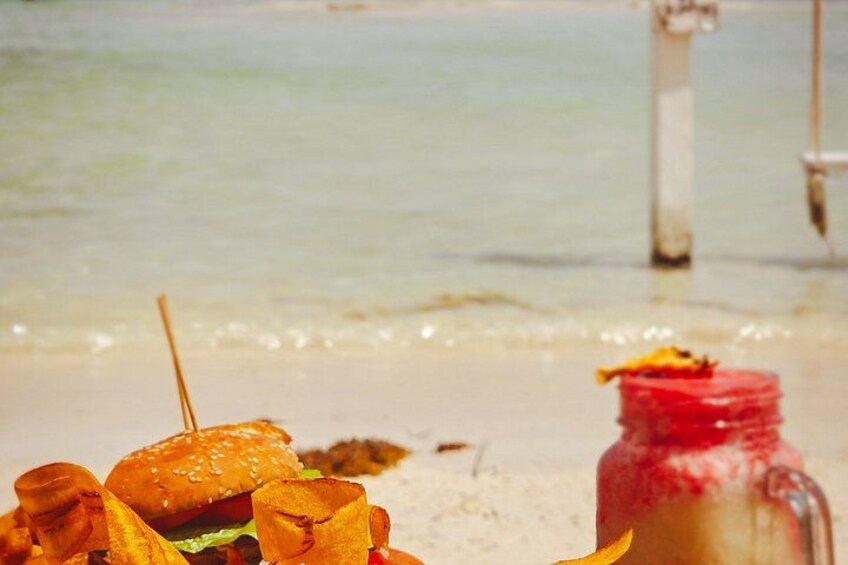 A beach scene with a burger, fries, and a red drink in the foreground, and the ocean in the background. 2