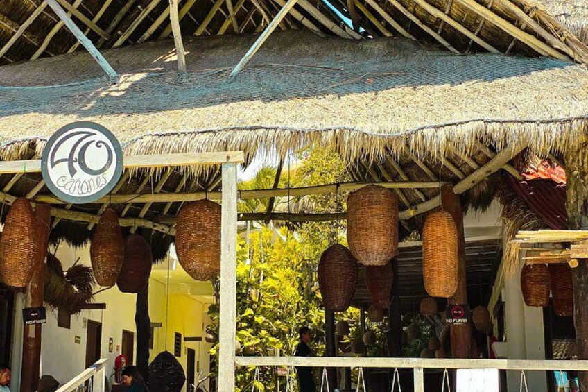 A thatched-roof structure with hanging baskets and a sign indicating '40 anos.' 5