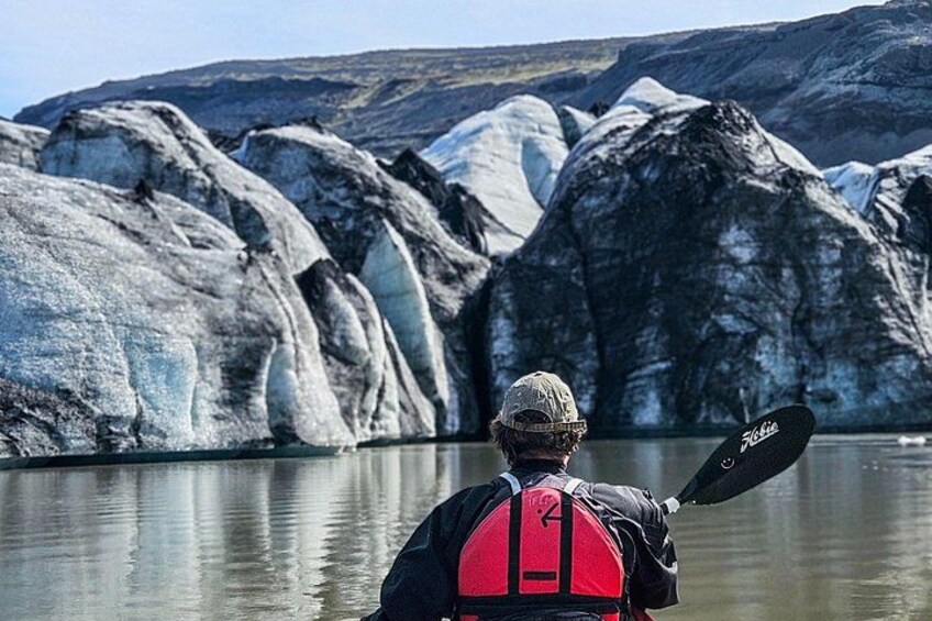 Una persona haciendo kayak en aguas tranquilas, con grandes glaciares al fondo. 1