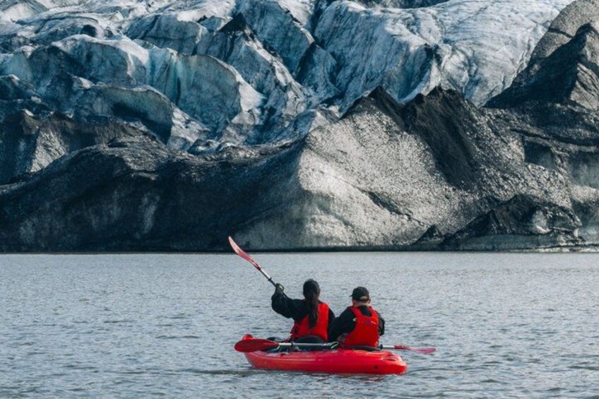 Dos personas kayakendo sobre aguas tranquilas, con un glaciar al fondo. 5