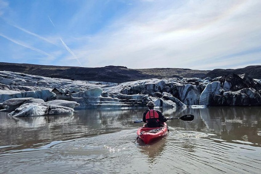 Un kayakista en kayak rojo sobre aguas tranquilas rodeado de formaciones de hielo. 4