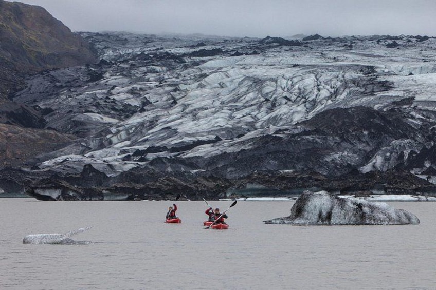 A glacier with kayakers in red kayaks. 2