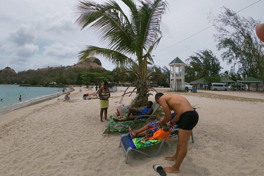 Una playa con gente tomando el sol, una palmera y una pequeña construcción blanca. 3