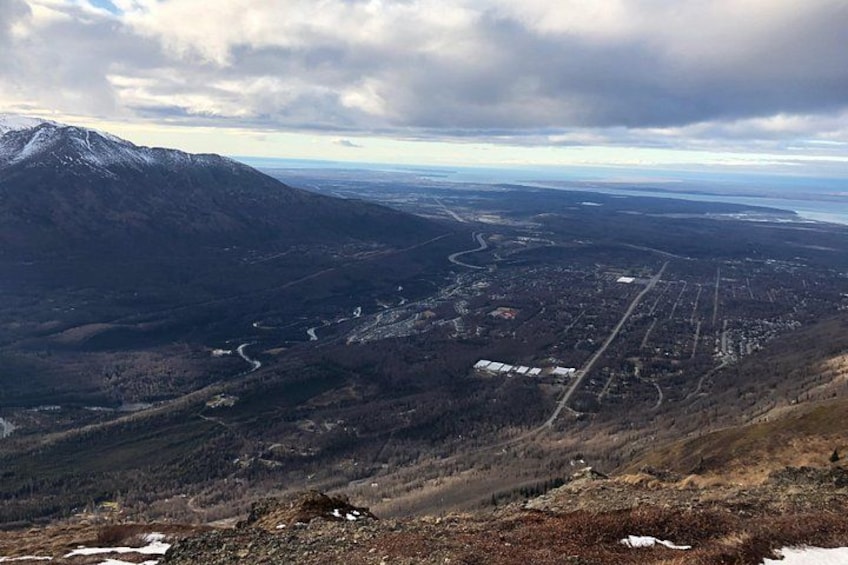 Ett bergigt landskap med en slingrande flod, ett snötäckt bergstopp och en dal med byggnader och vägar. 2