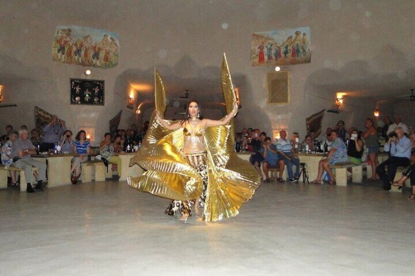 Una persona in un costume dorato si esibisce in una stanza di fronte a un pubblico. 2