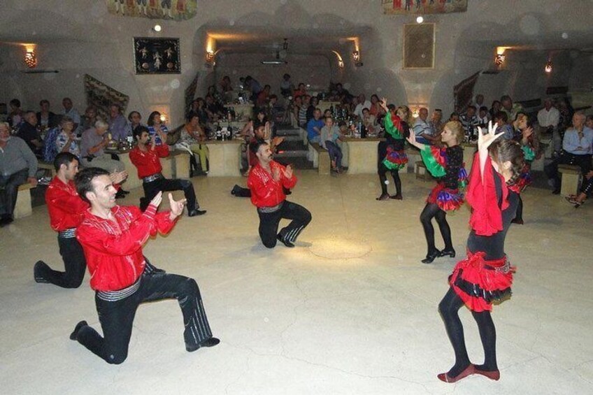 Un gruppo si esibisce in una danza tradizionale in una sala da ballo, di fronte a un pubblico. 1