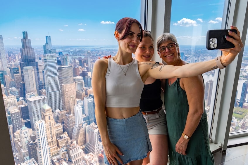 Three people taking a selfie with a cityscape in the background. 5