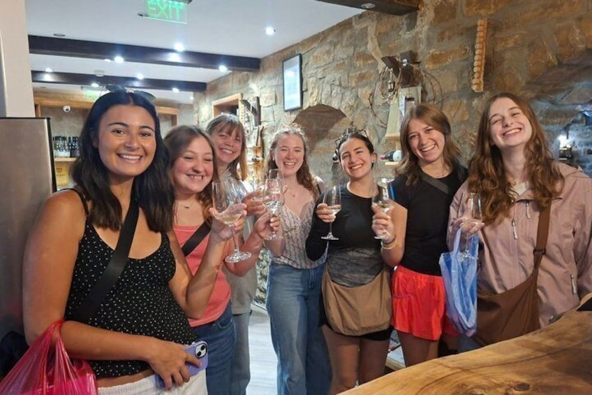 A group of people standing indoors, holding glasses, possibly at a social event. 2