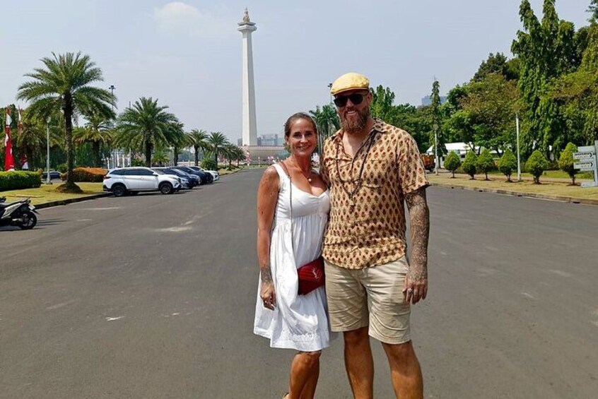 A man and a woman standing on a road with a tall tower in the background. 3