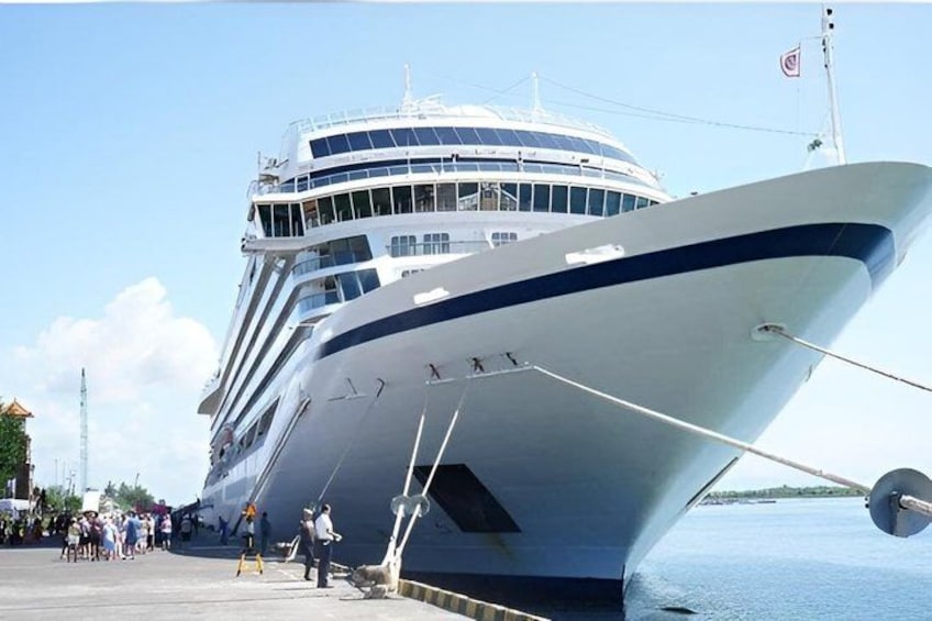 Un gran crucero amarrado en un puerto, con gente caminando. 1